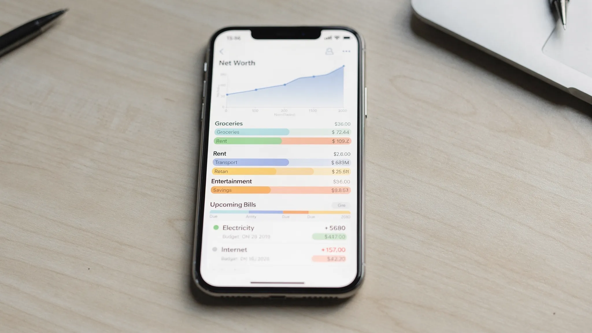 A modern iPhone showing a clean personal finance dashboard with monthly spending categories, budget vs actual bars, upcoming bills, and a net worth trend line in a simple, uncluttered interface.